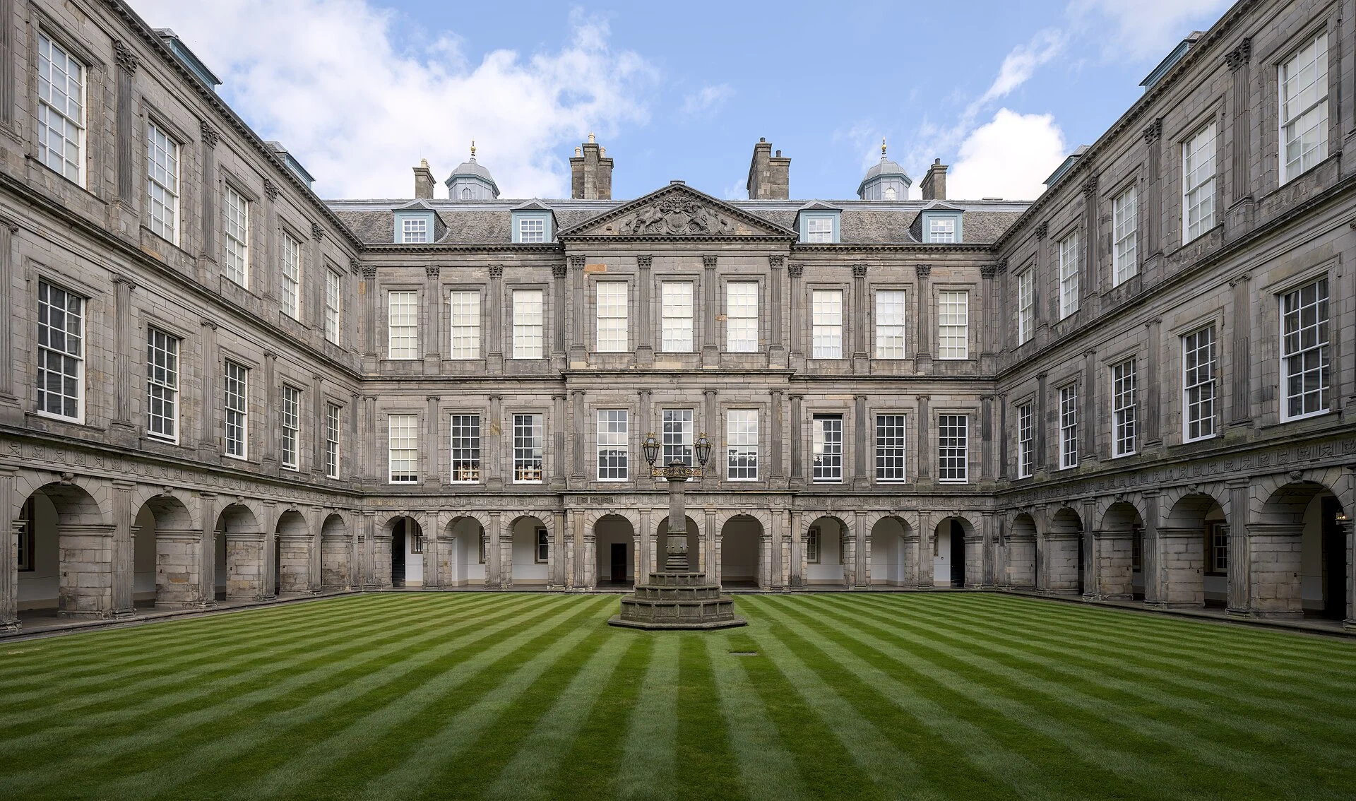 Der Innenhof (Quadrangle) des Palace of Holyroodhouse in Edinburgh mit Arkadengängen und gestreiftem Rasen.