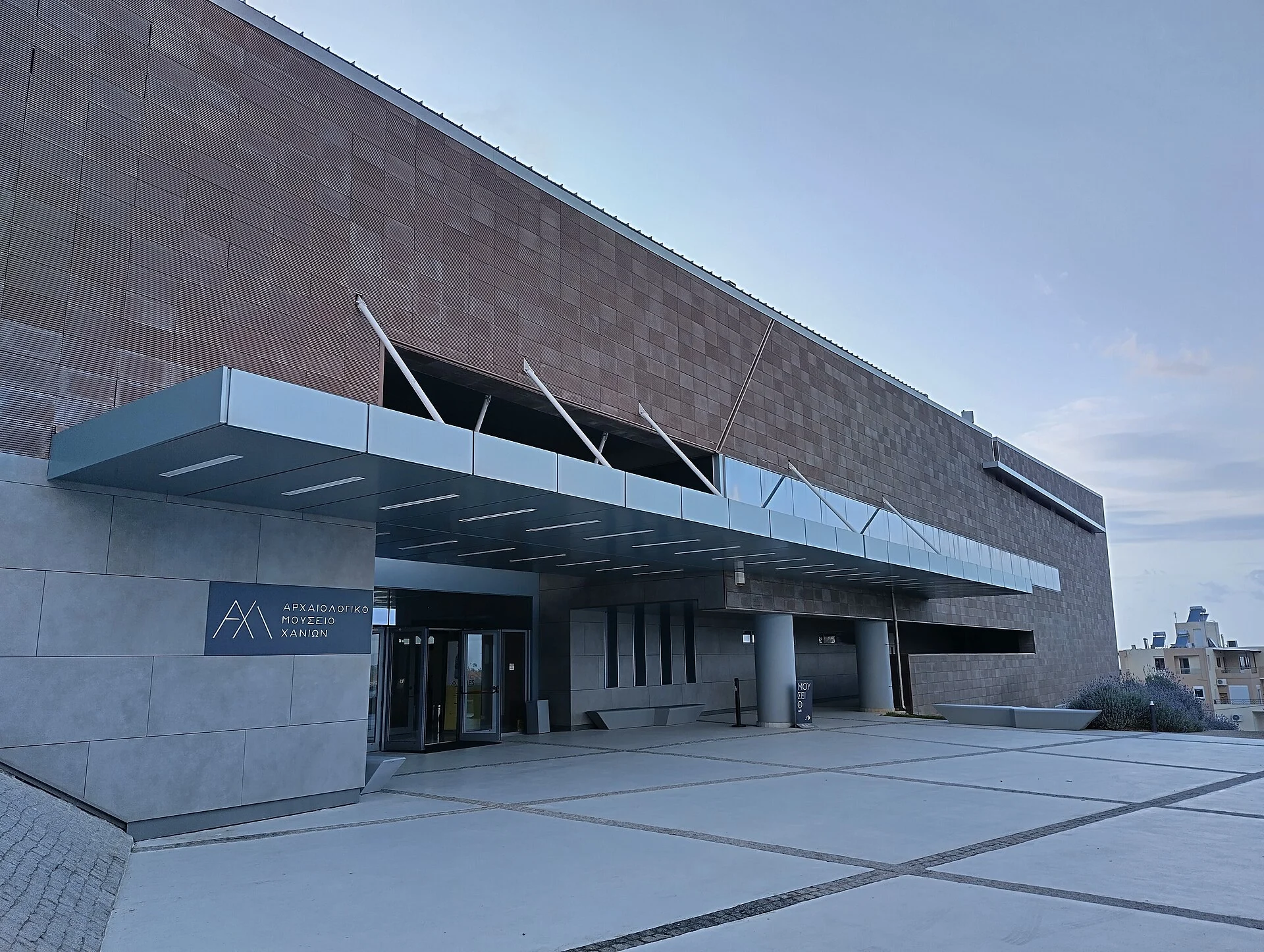 Eingang des neuen Archäologischen Museums Chania in Chalepa/Souda mit vorgezogenem Vordach und griechischer Beschilderung.