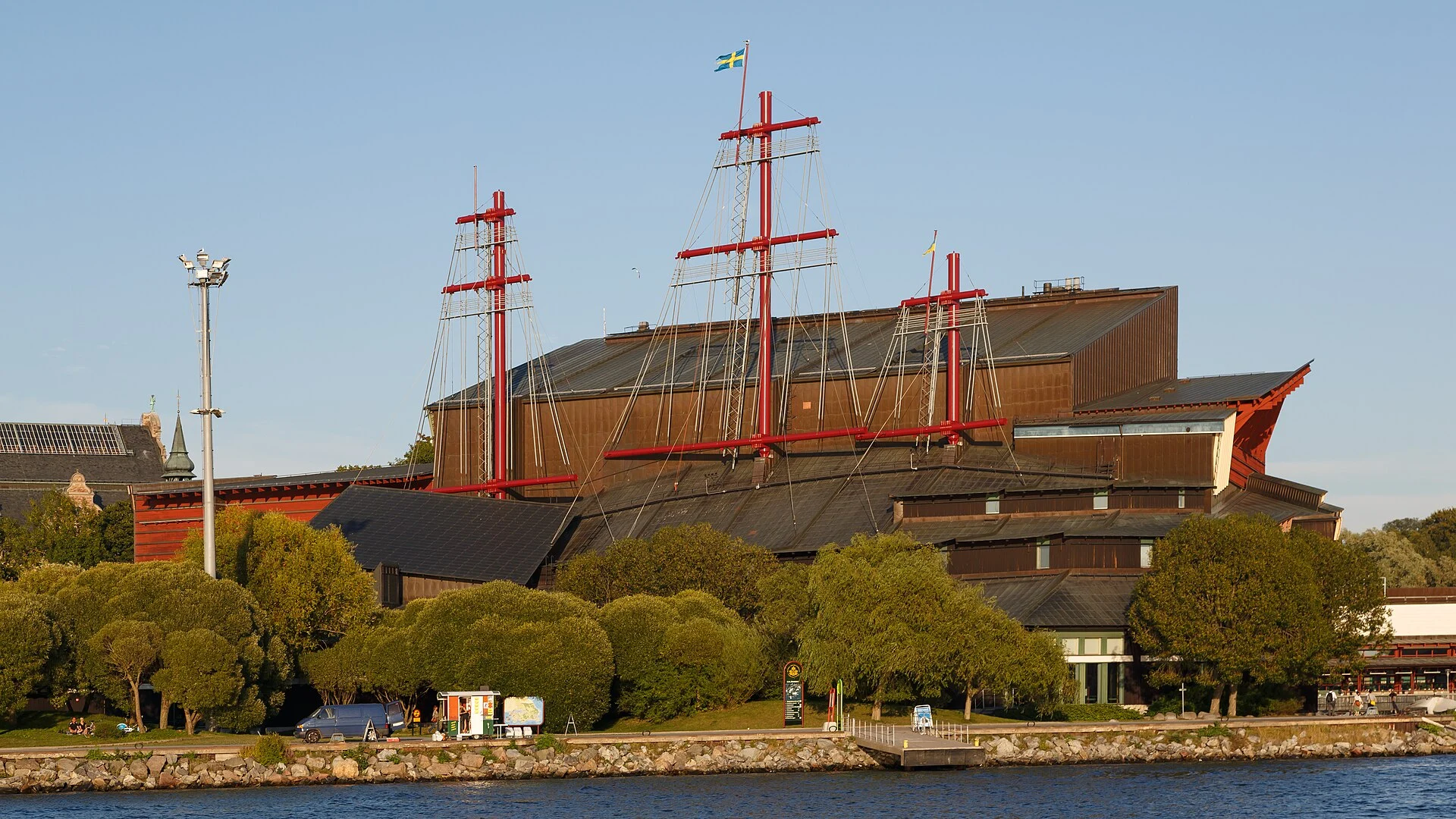 Das Vasa-Museum in Stockholm mit seinen roten Mastattrappen und dem Kupferdach, vom Wasser aus gesehen.