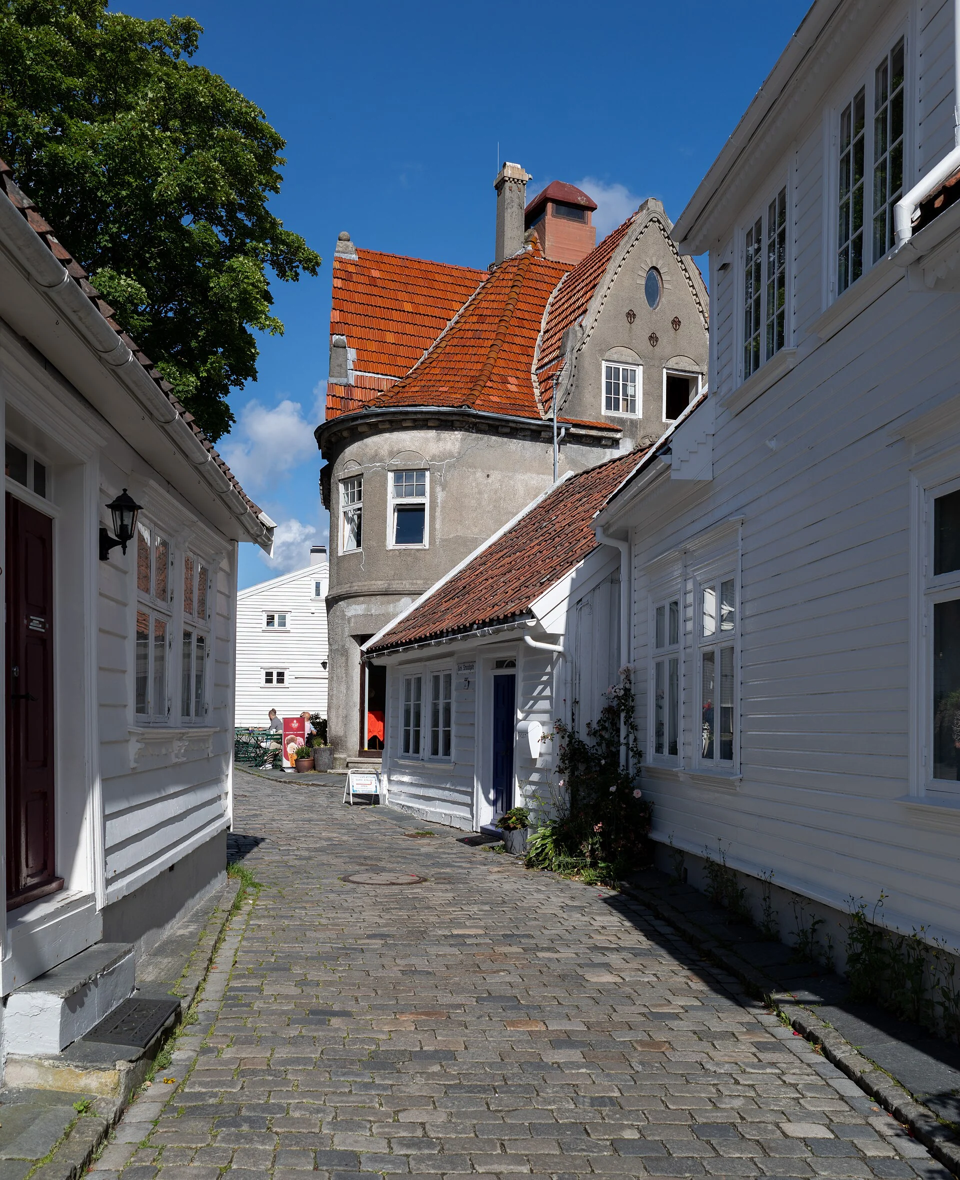 Kopfsteinpflastergasse Øvre Strandgate mit weißen Holzhäusern und einem Haus mit Rundturm in Gamle Stavanger.