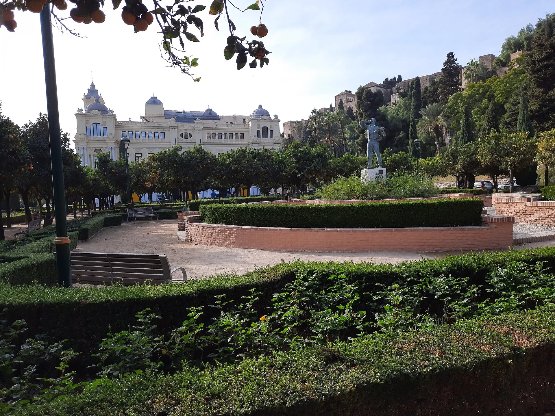 Blick über den Park und das Rathaus von Málaga hinauf zur Festung Alcazaba auf dem Berg