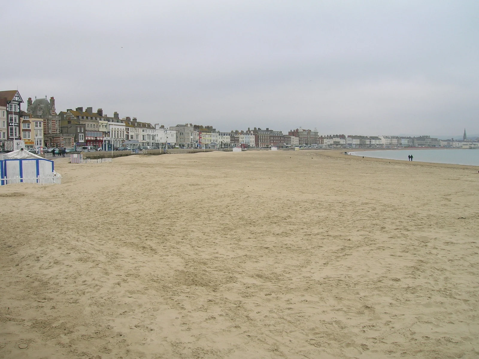 Der weite Sandstrand von Weymouth mit der georgianischen Häuserfront der Esplanade im Hintergrund.