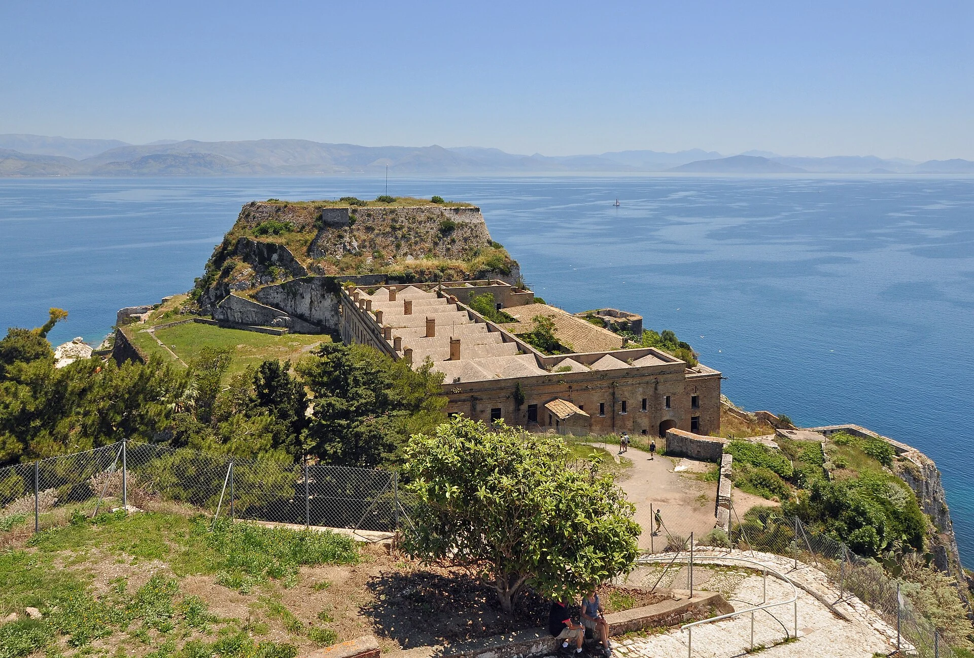Ostteil der Alten Festung von Korfu mit Kasernengebäuden und dem felsigen Hügel der Landzunge im Meer.