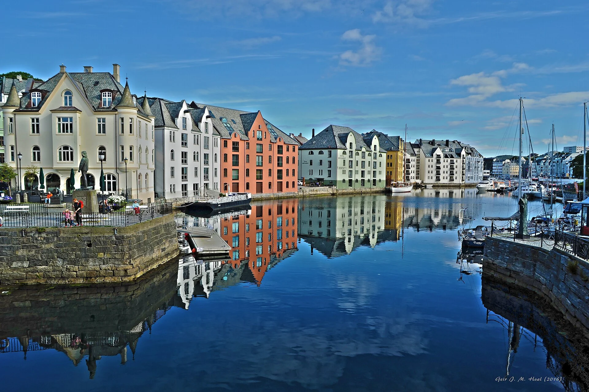 Farbige Jugendstilhäuser mit Türmchen spiegeln sich im Kanal Brosundet in Ålesund.