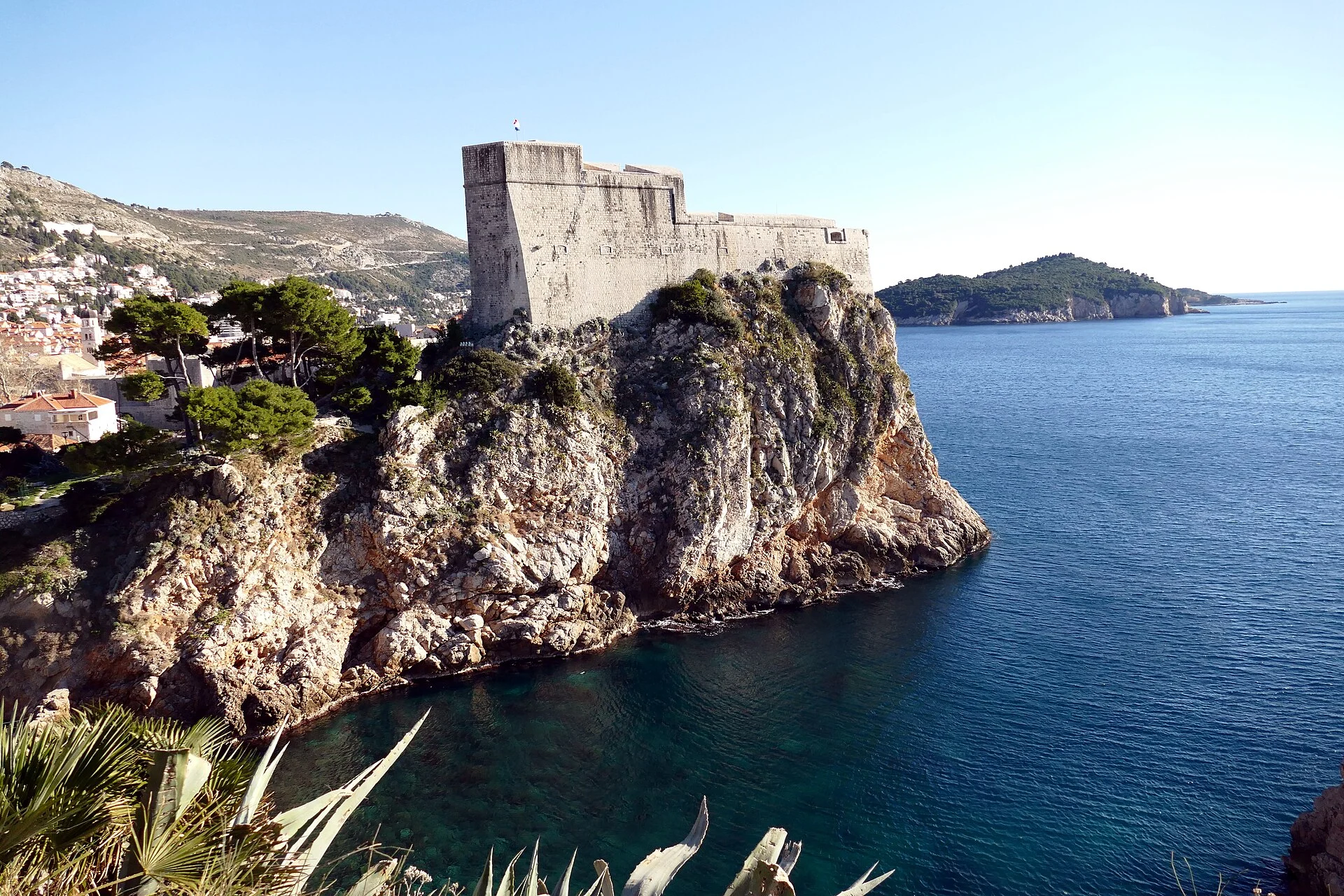 Die Festung Lovrijenac in Dubrovnik auf ihrem steilen Felsen über dem Meer, im Hintergrund die Insel Lokrum bzw. die Küste.